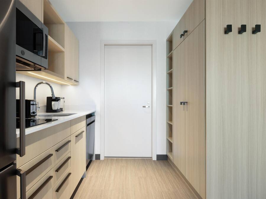 A modern kitchen with a built-in microwave, a coffee maker, and a stainless steel refrigerator.