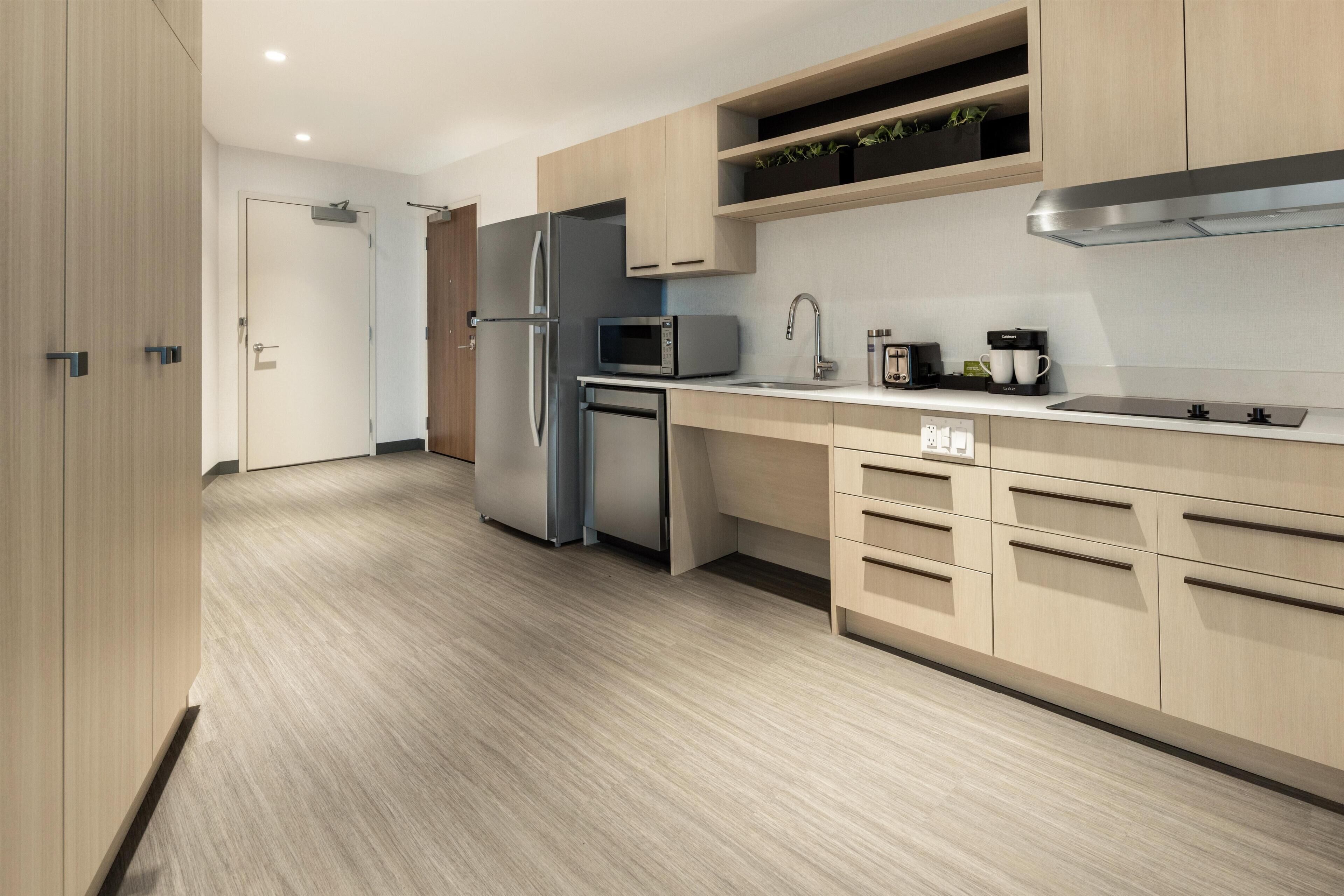 Una cocina moderna con armarios de madera, un refrigerador de acero inoxidable, un microondas y un lavamanos.