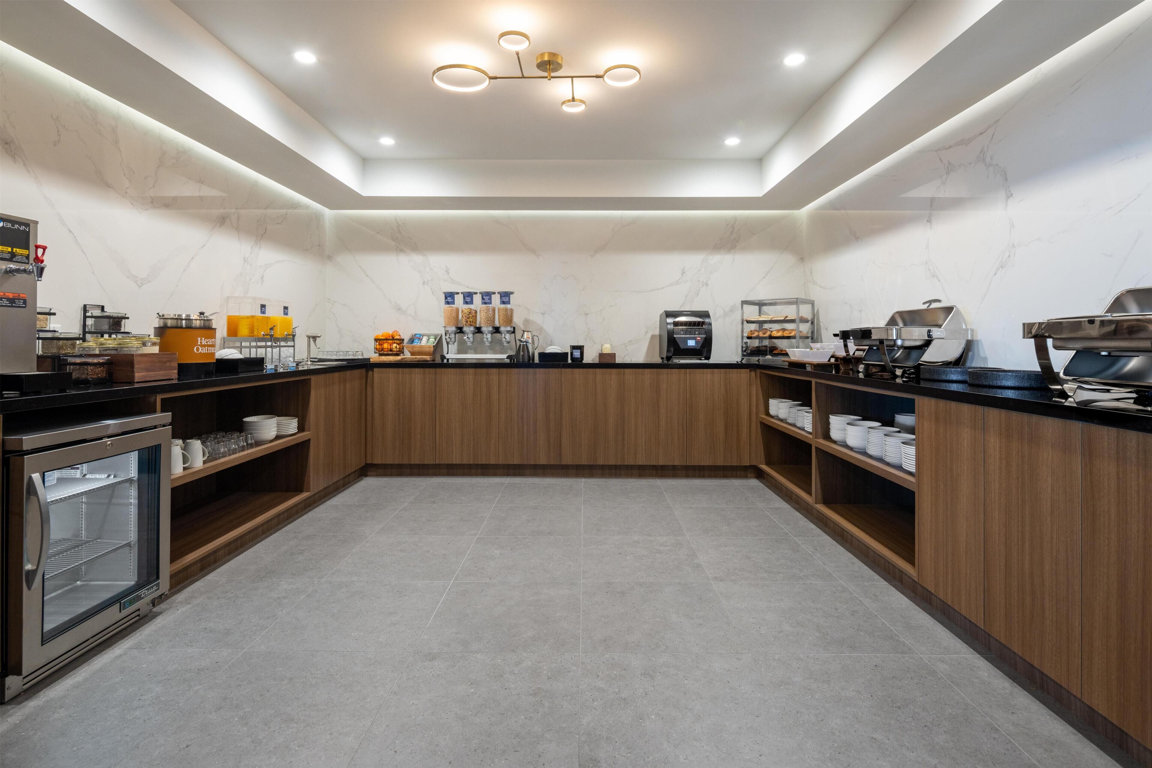 A modern kitchen with a marble backsplash, wooden cabinets, and a built-in coffee station.