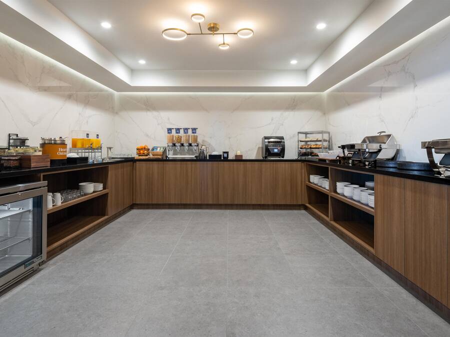 A modern kitchen with a marble backsplash, wooden cabinets, and a built-in coffee station.