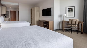 A hotel room with two beds, a desk, a chair, a TV, and a wardrobe.