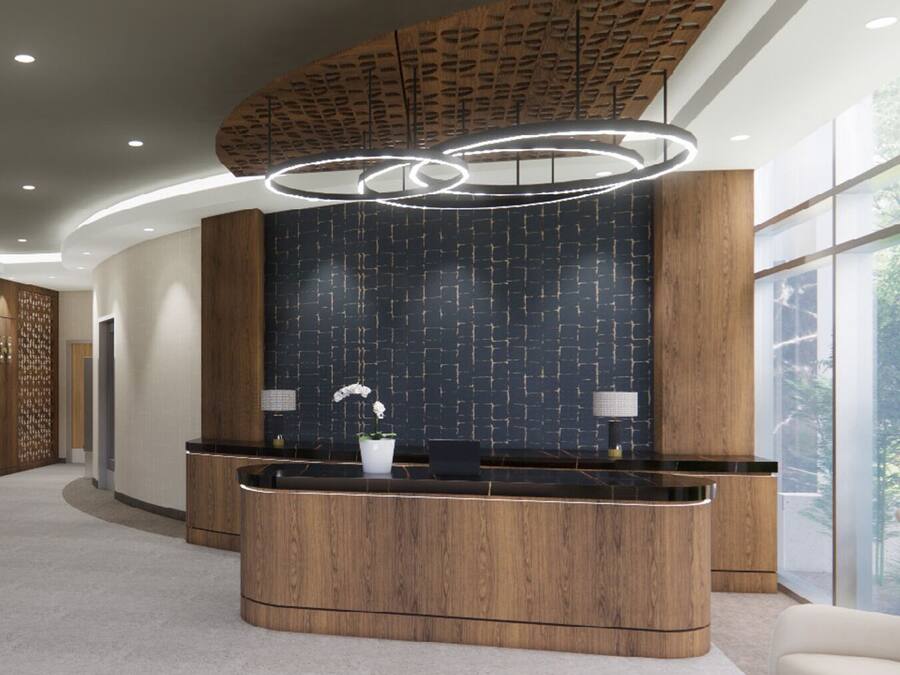 A reception area with a curved wooden reception desk, a dark patterned wall, and a modern light fixture.