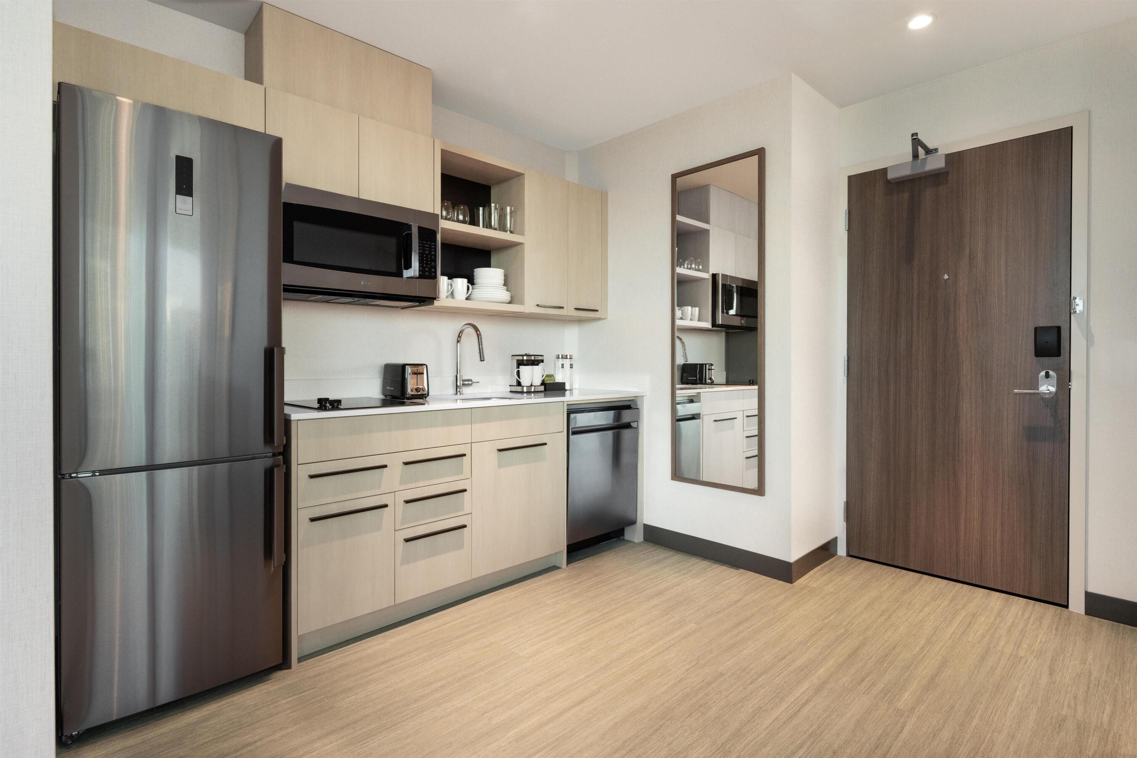 A modern kitchen with stainless steel appliances, wooden cabinets, and a built-in microwave.