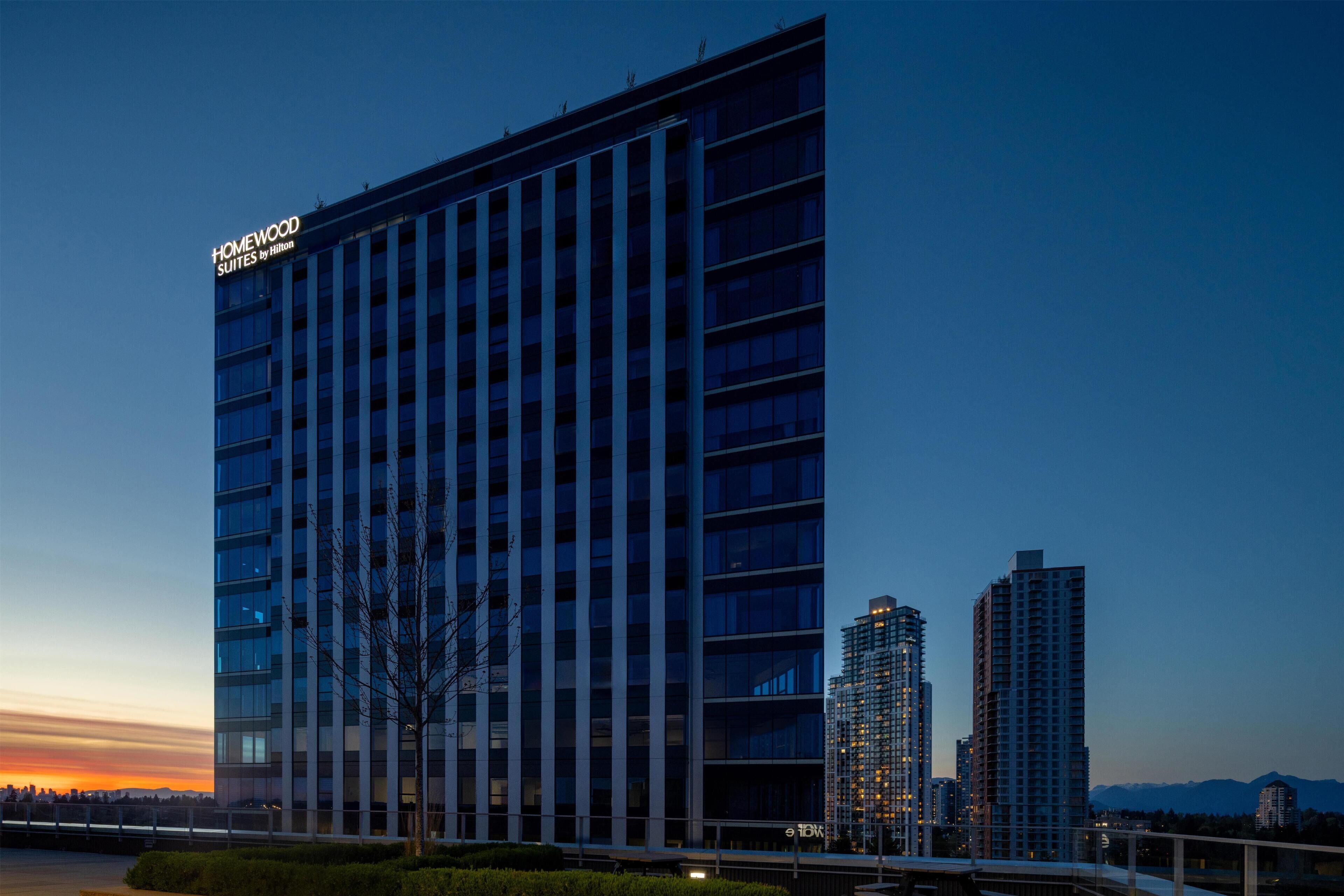 A modern hotel building with a sign indicating it is a Homewood Suites by Hilton.