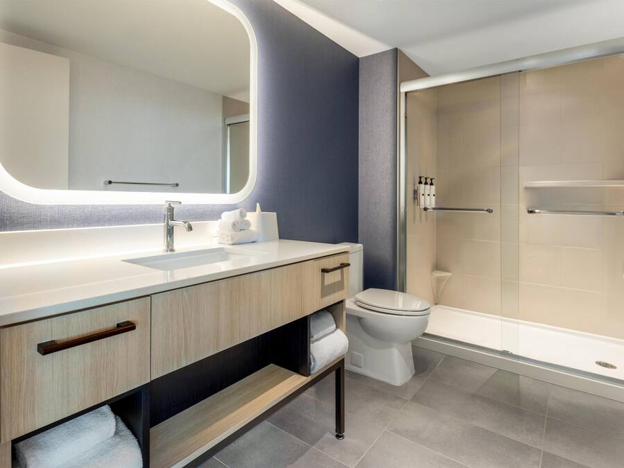 Un bagno moderno con uno specchio grande, un lavandino, un water e una cabina doccia in vetro.