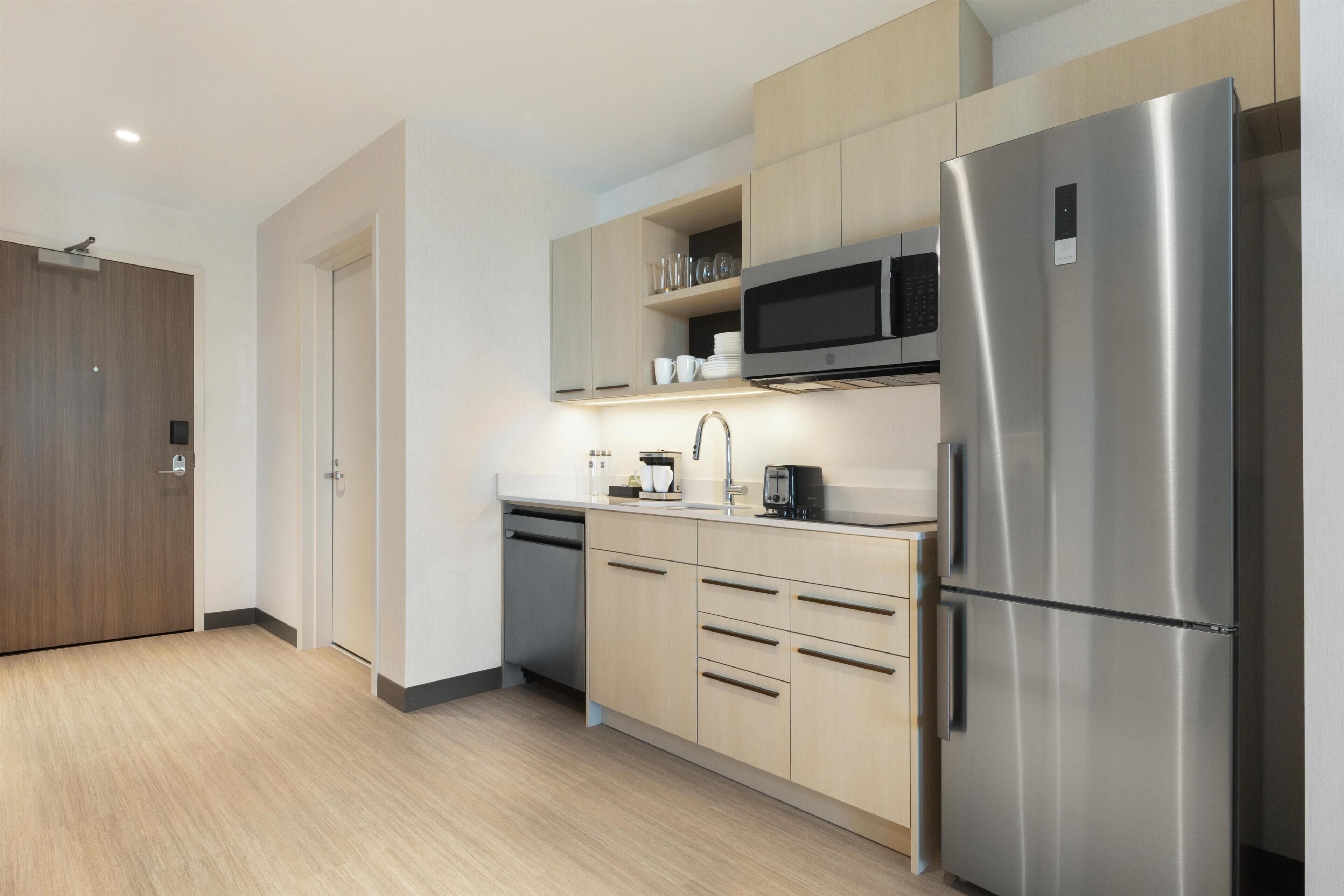 Una cocina moderna con electrodomésticos de acero inoxidable, armarios de madera y un microondas integrado.