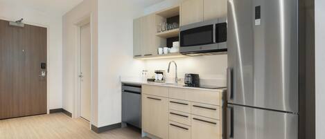 Una cocina moderna con electrodomésticos de acero inoxidable, armarios de madera y un microondas integrado.