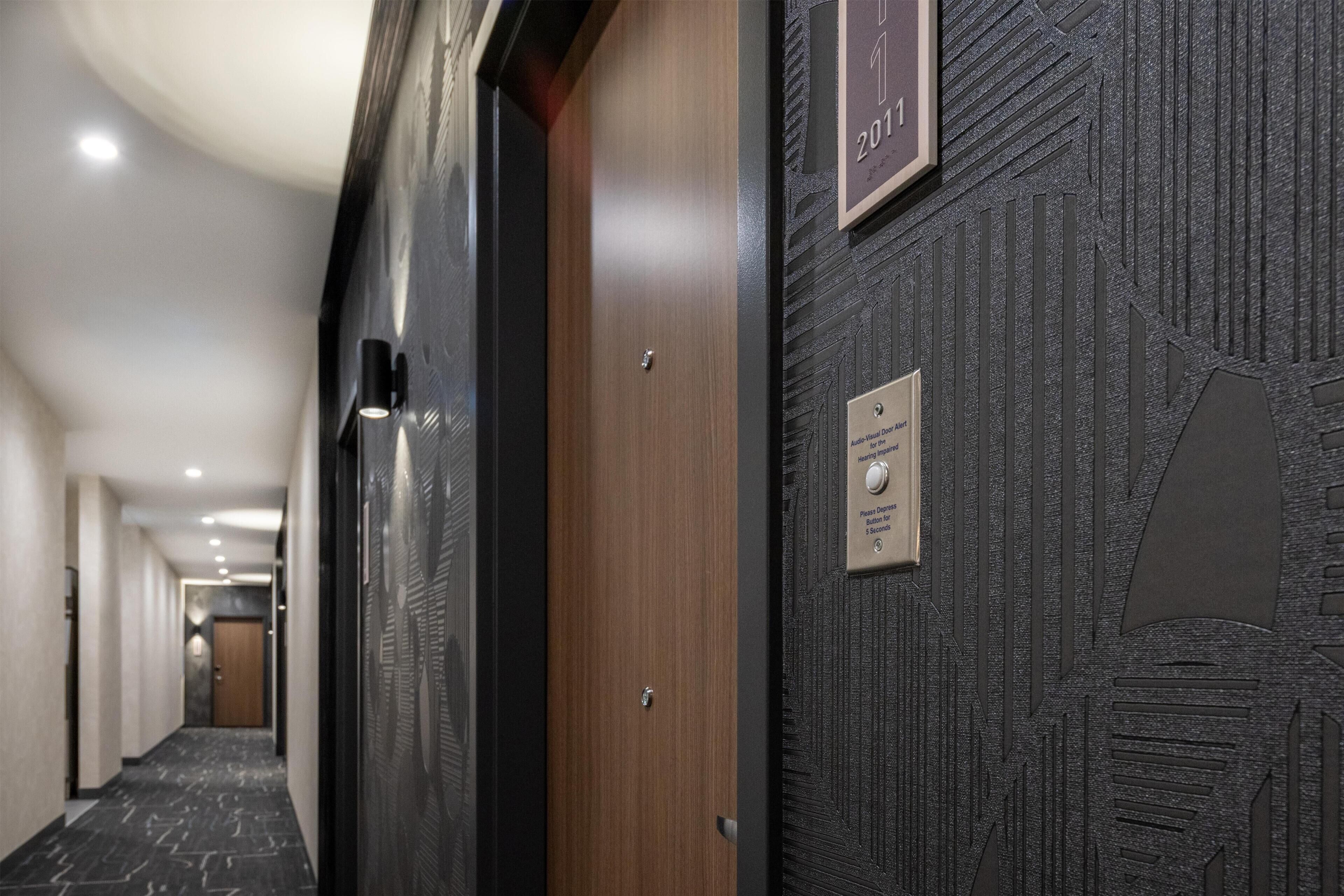 A hotel hallway with a wooden door, a textured wall, and a sign indicating the year 2011.