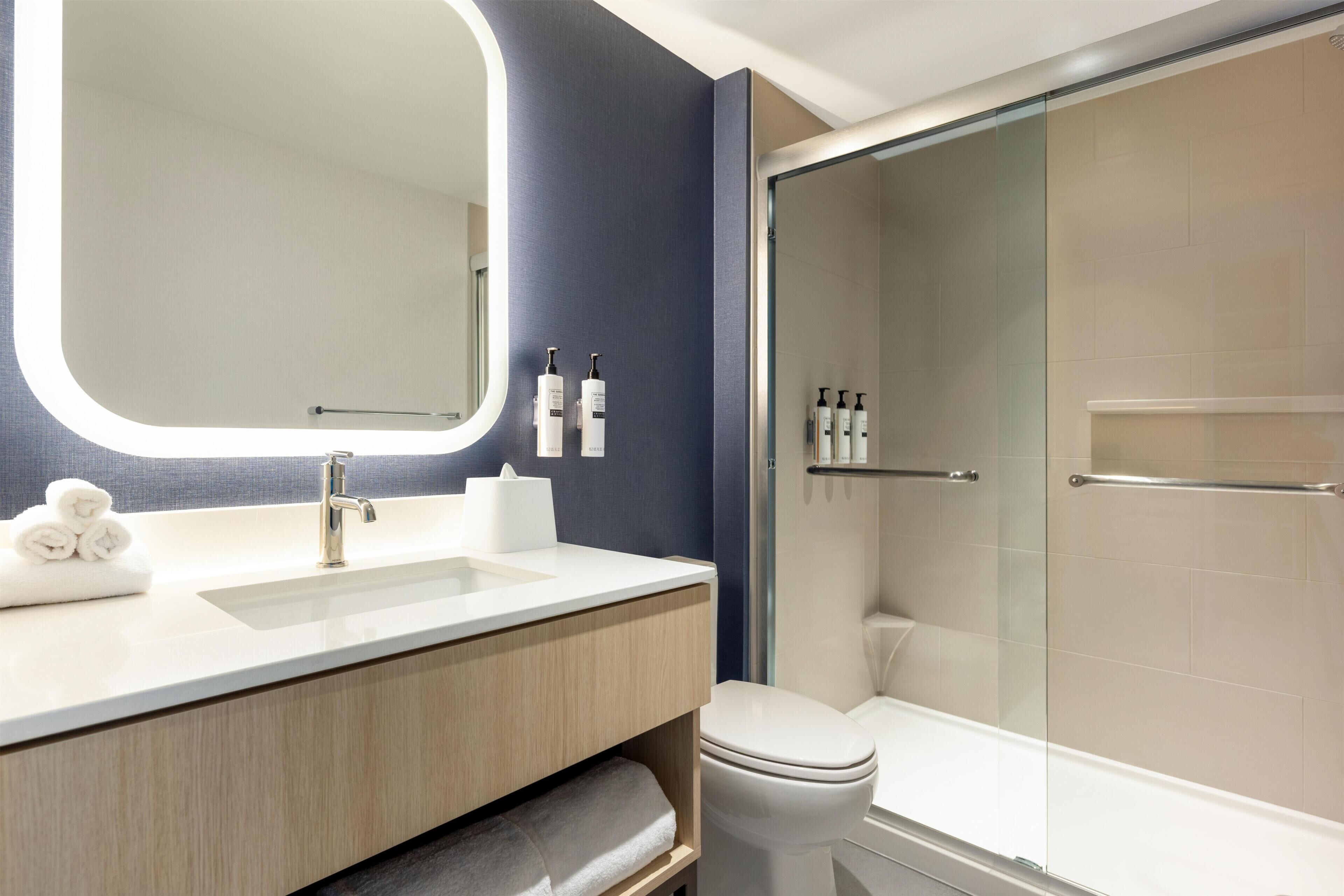 Ein modernes Badezimmer mit großem Spiegel, zwei Waschbecken, Toilette und einer Duschkabine.