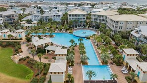 Un complex turístic amb diverses piscines, palmeres i vistes a la platja.