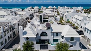 Zona residencial a la costa amb edificis blancs, cel blau clar i l'oceà al fons.