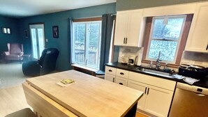 Une cuisine moderne avec des meubles blancs, une table à manger en bois et un four encastré.