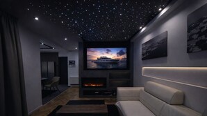 A modern living room with a starry ceiling, a large flat-screen TV, a fireplace, and a comfortable sofa. - Legacy Marine 3 – Luxury Designer Penthouse in Zadar (Zadar)