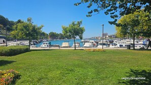 A marina with boats docked, a grassy area with flowers, and a clear blue sky. - Legacy Marine 3 – Luxury Designer Penthouse in Zadar (Zadar)