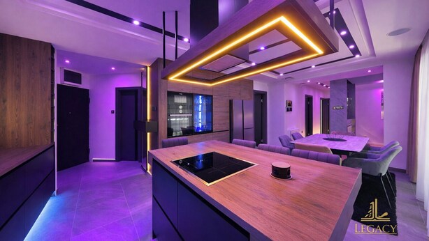 A modern kitchen with a central island, built-in appliances, and a dining area with a table and chairs. - Legacy Marine 3 – Luxury Designer Penthouse in Zadar (Zadar)