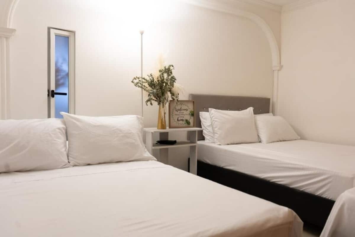 A hotel room with two beds, a bedside table with a vase, and a welcome sign.