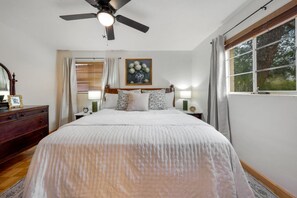 A bedroom with a bed, a ceiling fan, a nightstand, a dresser, and a window with curtains. - Cozy 3BR / Fenced Yard & Grill / Near TMC & U of A (Tucson)
