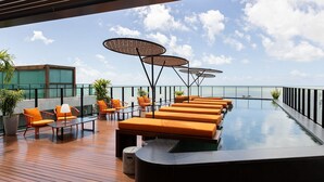 A rooftop infinity pool with lounge chairs and umbrellas, overlooking the ocean. - Setai Edition #206 - Waterfront by Carpediem (João Pessoa)