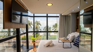 A modern room with a large window, a bed with pillows, a small table with a cup, and a TV mounted on the wall. - Setai Edition #206 - Waterfront by Carpediem (João Pessoa)