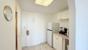 A compact kitchen with white cabinets, a refrigerator, a coffee maker, and a microwave. - Cozy Studio at St. Johns – Steps to Beach (Myrtle Beach)