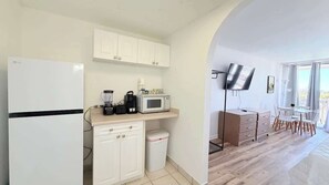 A compact kitchen with white cabinets, a microwave, a coffee maker, and a trash bin. - Cozy Studio at St. Johns – Steps to Beach (Myrtle Beach)