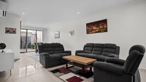 A modern living room with a sofa set, a coffee table, and a rug. - Spacious 3-bed Townhouse in Coburg (Melbourne)