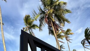 A gated entrance with a sign reading "ACESSO A PRAIA" and a QR code for access. - Apê Maré Blue - Seu Paraíso à beira-mar! (ILHEUS)
