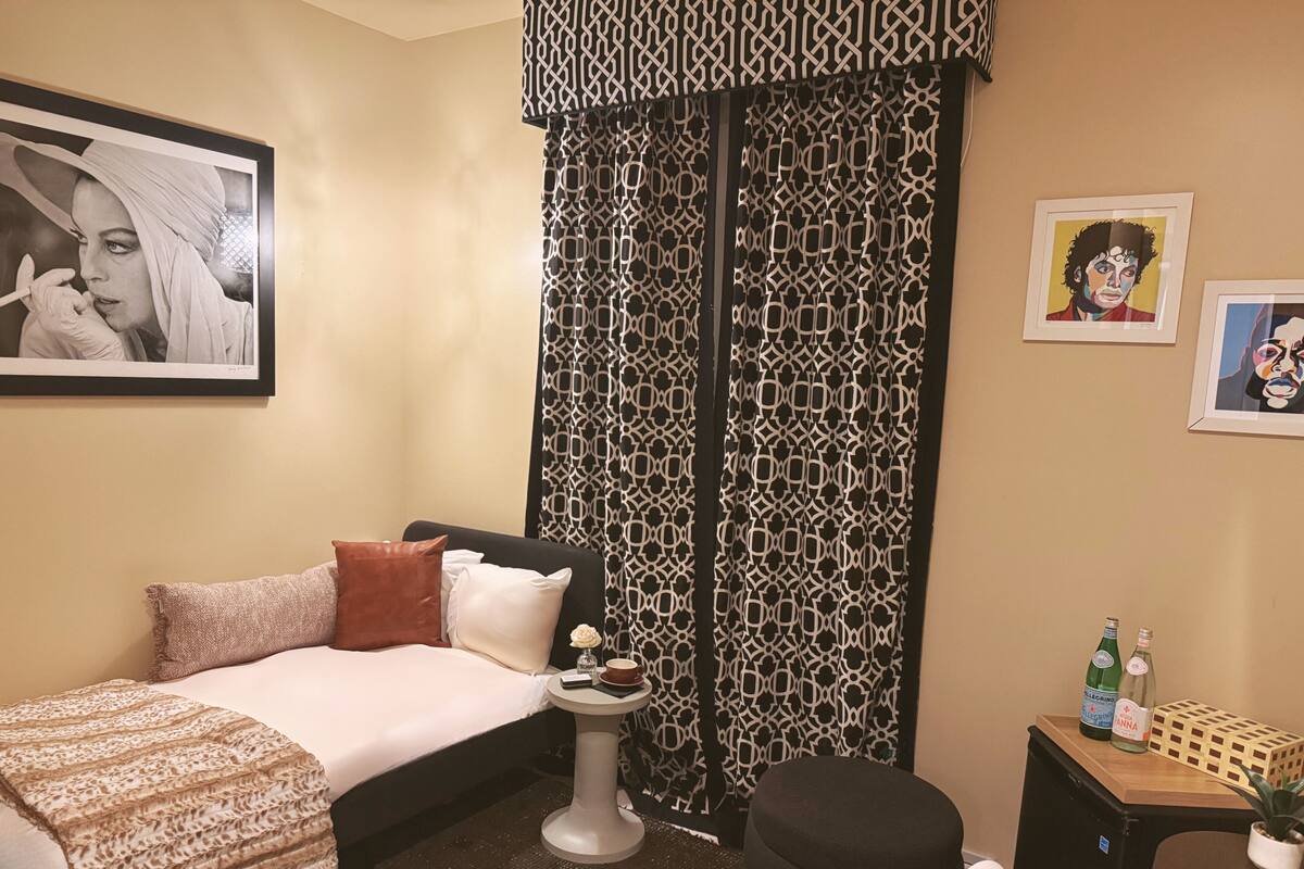 A hotel room with a bed, bedside table, and a small desk with a chair.