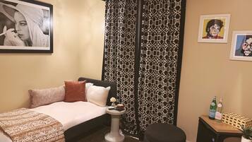 A hotel room with a bed, bedside table, and a small desk with a chair.