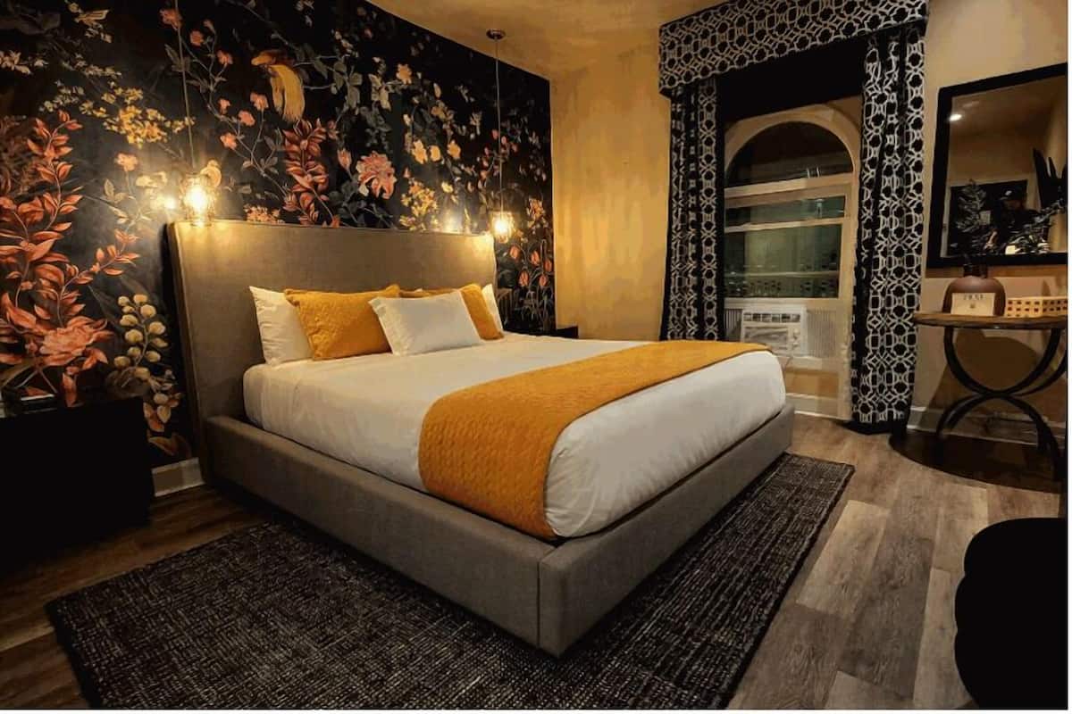 A modern bedroom with a large bed, a decorative wall, and a unique patterned curtain.