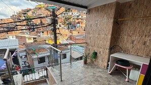 Een balkon met uitzicht op een dichtbebouwd stadsgebied, met betegelde vloer en houten wand.