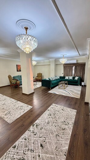 A spacious living room with a sectional sofa, two armchairs, a coffee table, and a chandelier. - Zamalek Club View Residence (Giza Governorate)