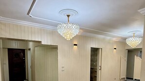Um corredor amplo com piso de madeira, paredes brancas e duas luminárias.