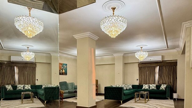 Uma sala de estar espaçosa com piso de madeira escura, espelhos grandes e um candelabro.