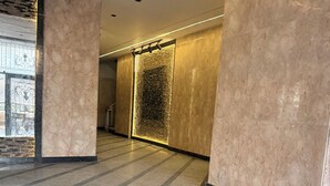 Um interior moderno com paredes de mármore, uma escadaria de pedra e um aplique na parede.