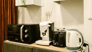 Eine Küchenzeile mit Mikrowelle, Kaffeemaschine, Toaster und Wasserkocher.