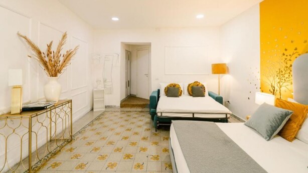 A modern bedroom with a bed, bedside table, lamp, and decorative plants. - Random Deluxe By Dimorra (Naples)