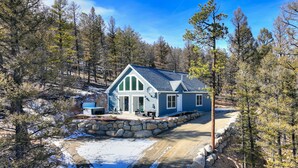A modern house with a stone foundation, large windows, and a covered outdoor area. - Cozy Cabin: Hot Tub + Fireplace, Near Breck (Fairplay)