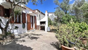 A white building with a tiled roof, wooden shutters, and a small outdoor area with a potted plant. - Casa Alma | Welcomely (Sas Murtas)