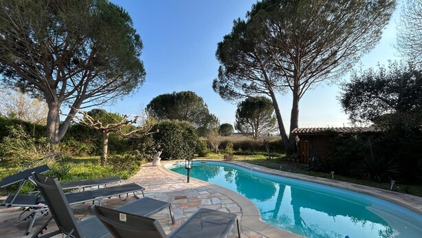 A swimming pool with lounge chairs and a stone patio.