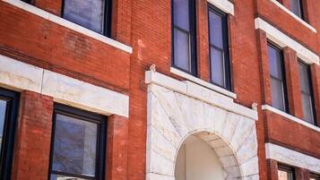 A red brick building with white trim, a stone archway, and a staircase leading to an entrance.