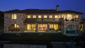 A two-story house with a stone facade, large windows, and a patio area.