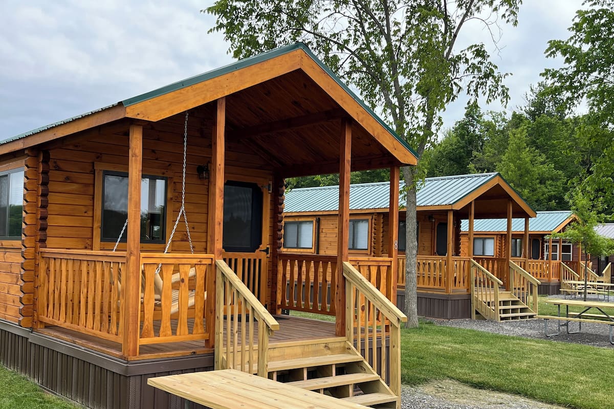 A wooden cabin with a porch, a staircase, and a picnic table.