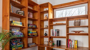 Una camera accogliente con scaffali di legno pieni di libri e giochi, un’area per nutrire animali domestici e un’ampia finestra vista alberi.
