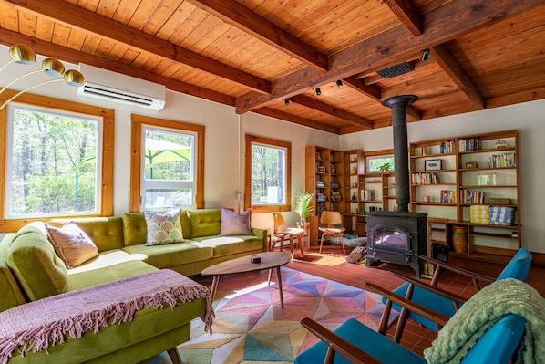 A cozy living room with a green sofa, a coffee table, a fireplace, and a bookshelf.