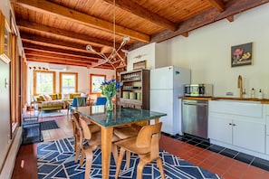 A kitchen with a dining area, wooden ceiling beams, and a refrigerator.