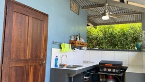 Uma cozinha compacta com fogão a gás embutido, pia e janela com vista para o verde.