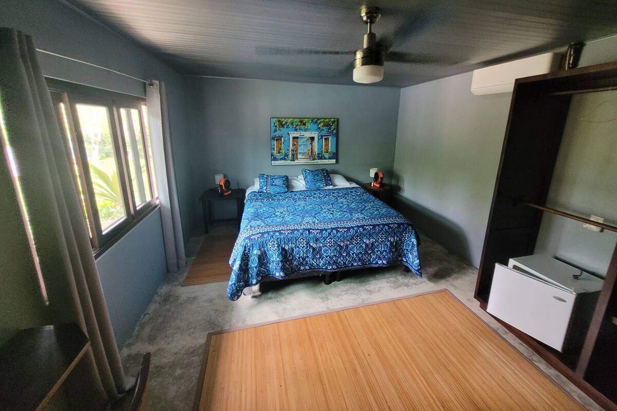 A bedroom with a bed, a ceiling fan, a nightstand, a dresser, and a window.