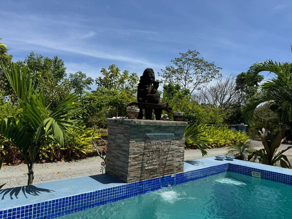 A statue on a stone pedestal by a pool with blue tiles, surrounded by tropical plants. - Inn at Punta Mala (Punta Mala)
