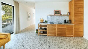 A modern kitchen with a marble countertop, wooden cabinets, and a view of greenery outside. - Casa Luisa Boutique Stay with Vegetable Garden and Sea View (Forio)